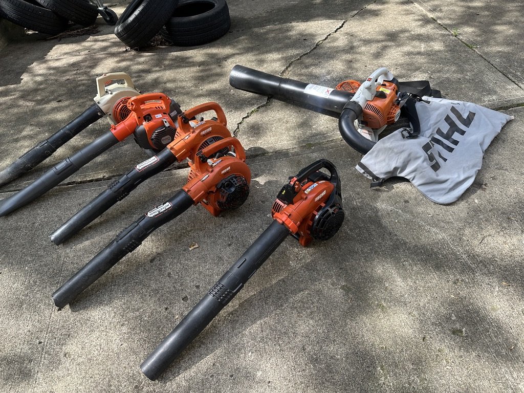 A row of gas leaf blowers on a driveway