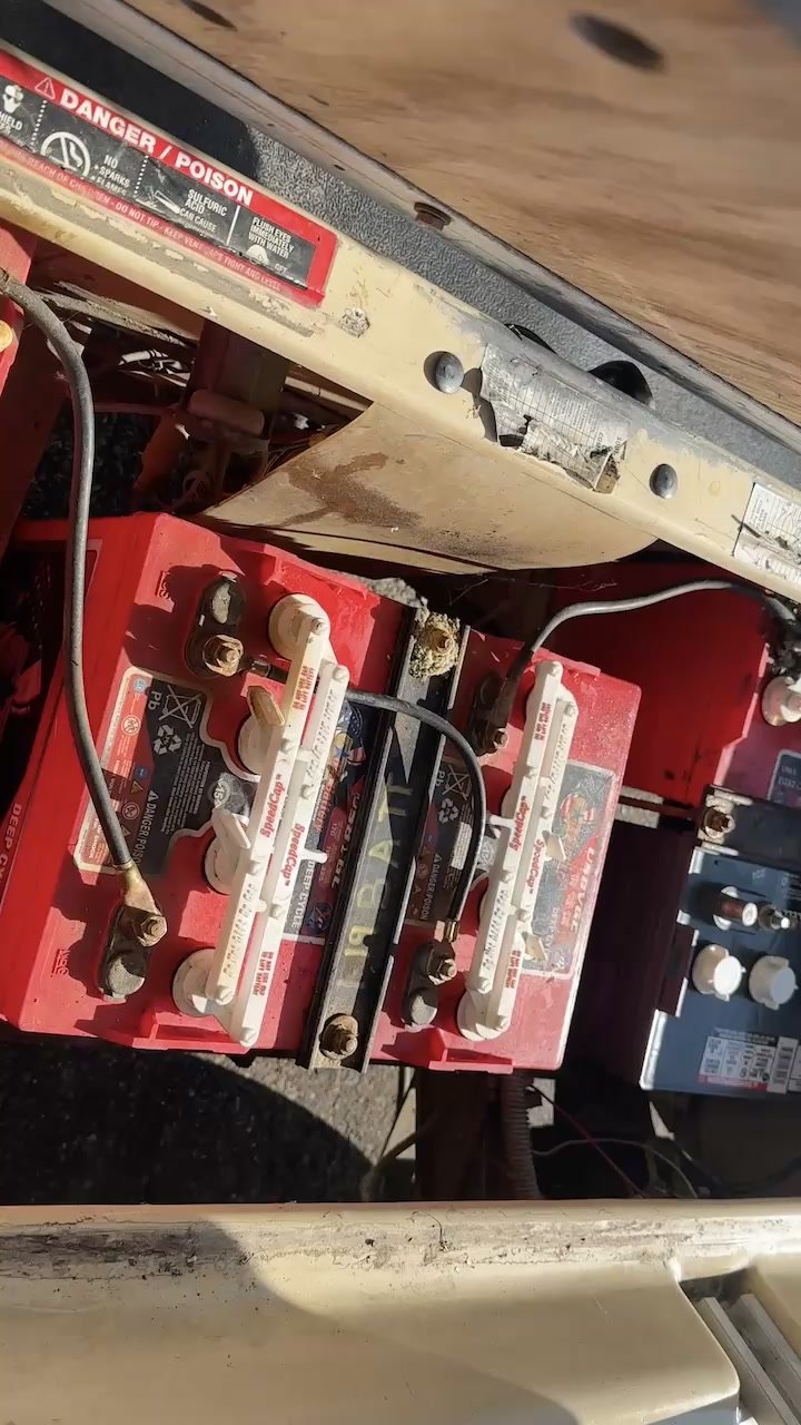 The Club Car's battery compartment opened up, showing red deep-cycle batteries with their vent caps