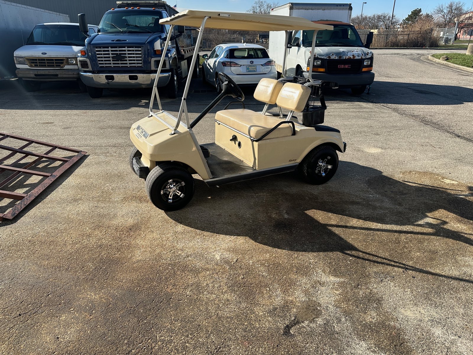 The tan Club Car parked in a lot with new chrome wheel covers
