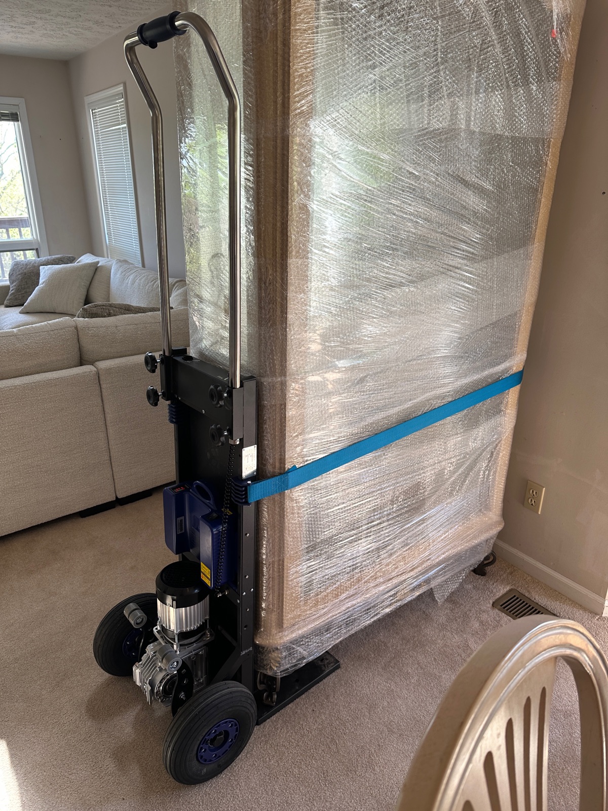 Electric stair-climbing dolly carrying a curio cabinet