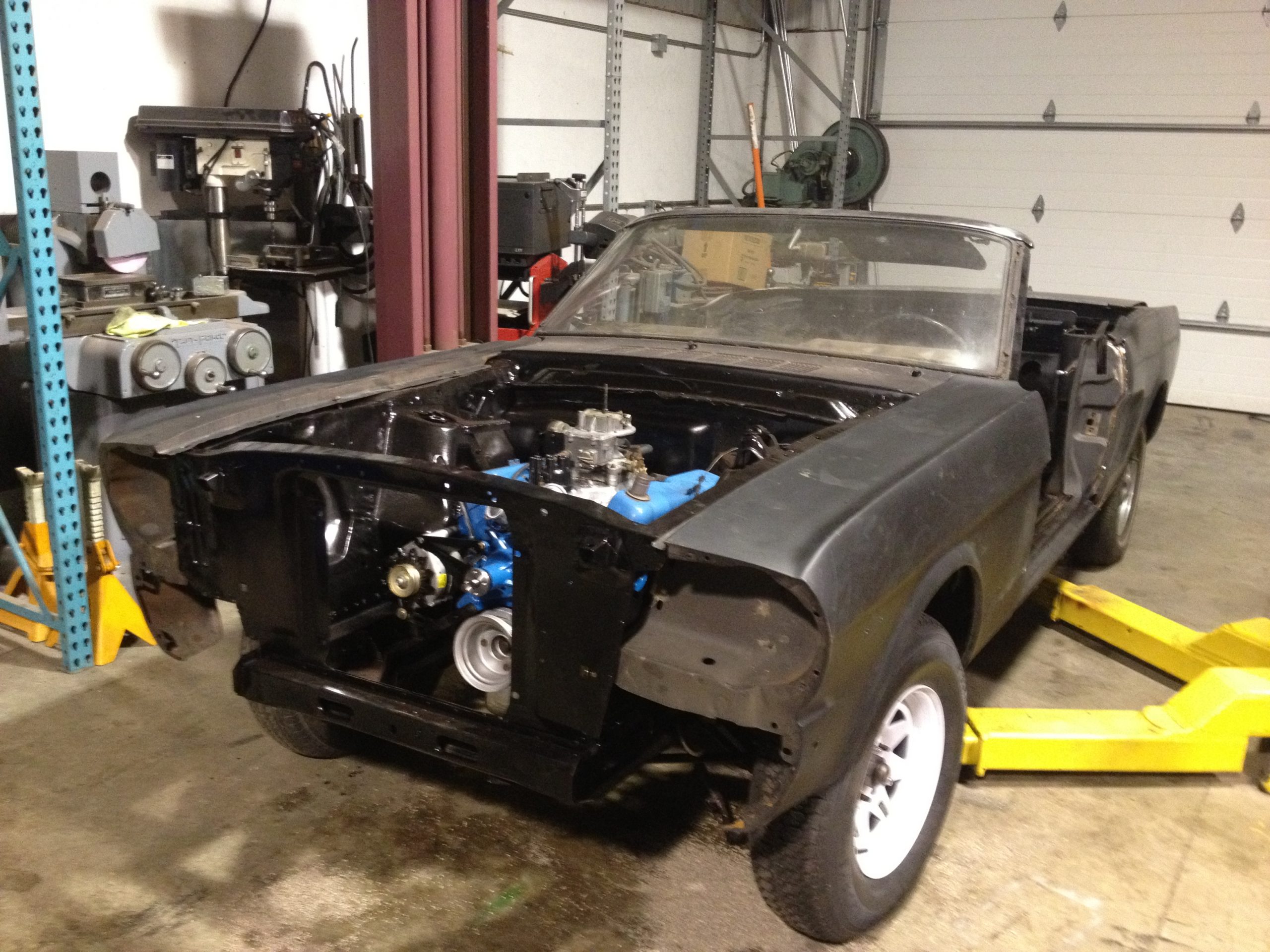 The 1966 Mustang in the shop with a blue Ford engine installed but the front sheet metal and trim still missing