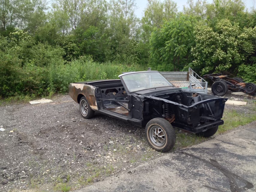The stripped 1966 Mustang convertible shell outdoors, missing its doors, front sheet metal, engine, and interior